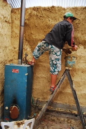Smearing mud on the straw-bale house, volunteering in Australia